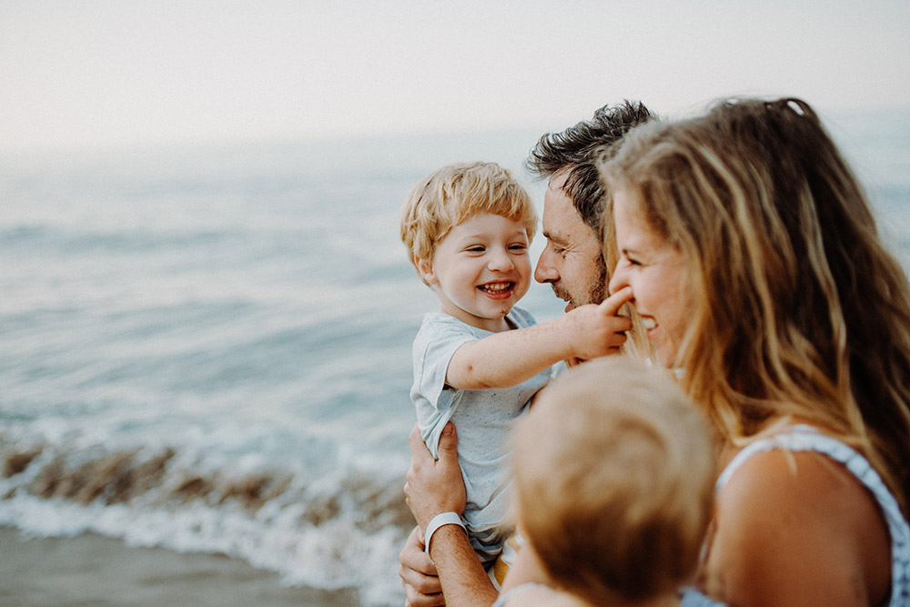 A young family with two toddler children standing on beach on summer holiday. Should I combine my pensions into one pot?